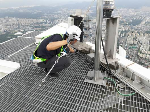 롯데월드타워 최상층부 랜턴구간에 설치된 피뢰침에 작업자가 와이어 설치 및 점검작업을 진행하고 있다. (출처 = 롯데물산)